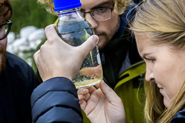 Personer tittar på flaska med vatten. foto.